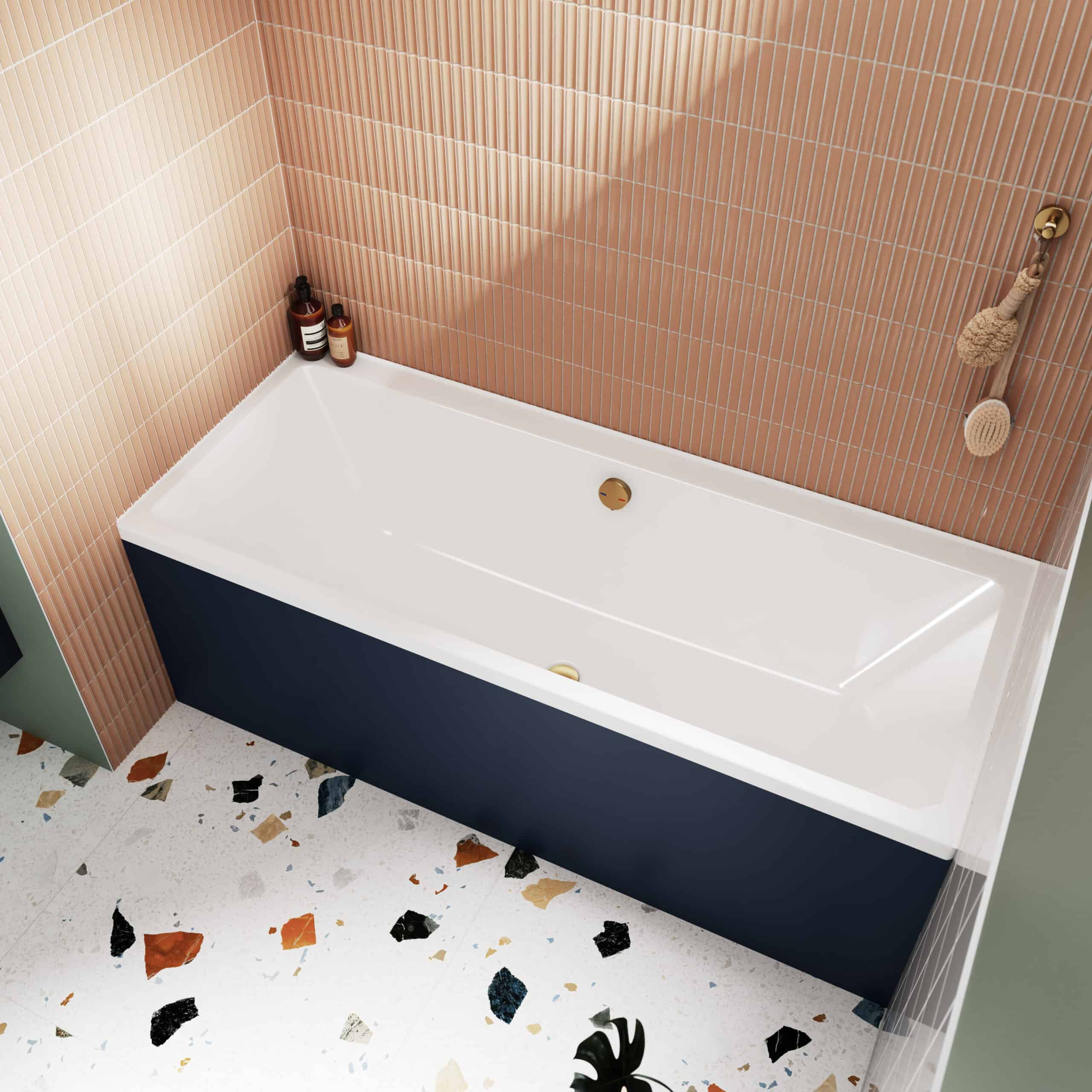 Modern white bathtub with gold fixtures in a stylish bathroom featuring pink tiled walls and terrazzo flooring. Ideal for luxury bathroom renovations and spa-like settings.