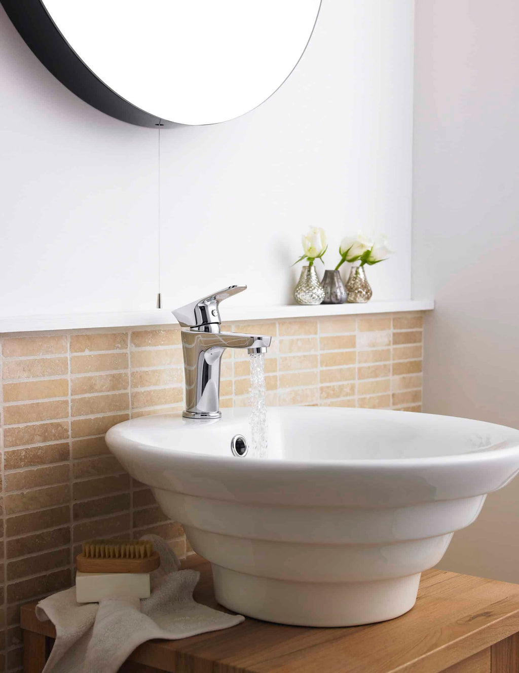 Elegant bathroom sink with chrome faucet, modern interior design, beige brick backsplash, and decorative flower vases, showcasing high-quality bathroom fixtures and stylish decor.