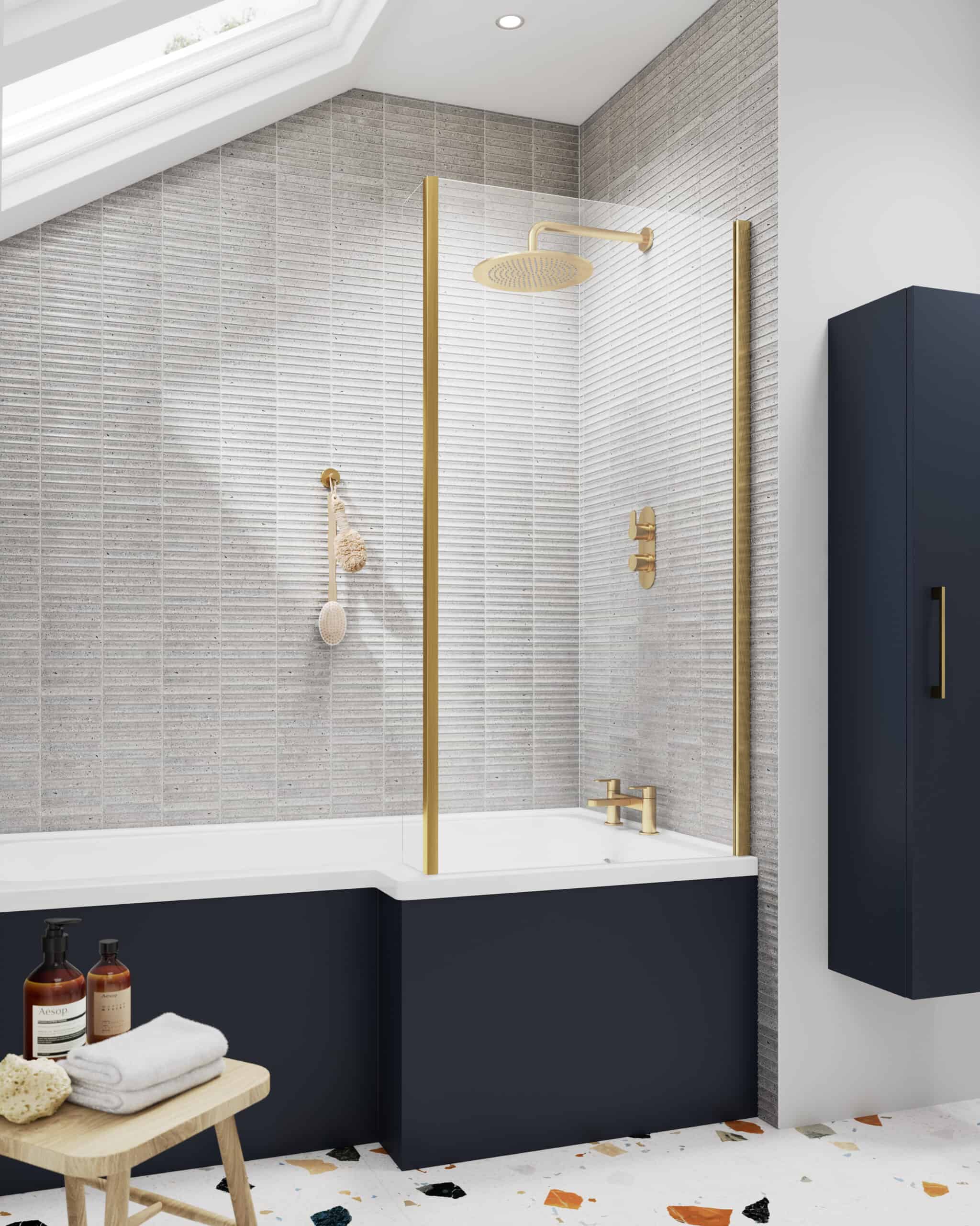 Shower with gold fixtures and grey tiled walls in modern bathroom, featuring a blue bath panel and sleek storage cabinet, perfect for contemporary bathroom designs.