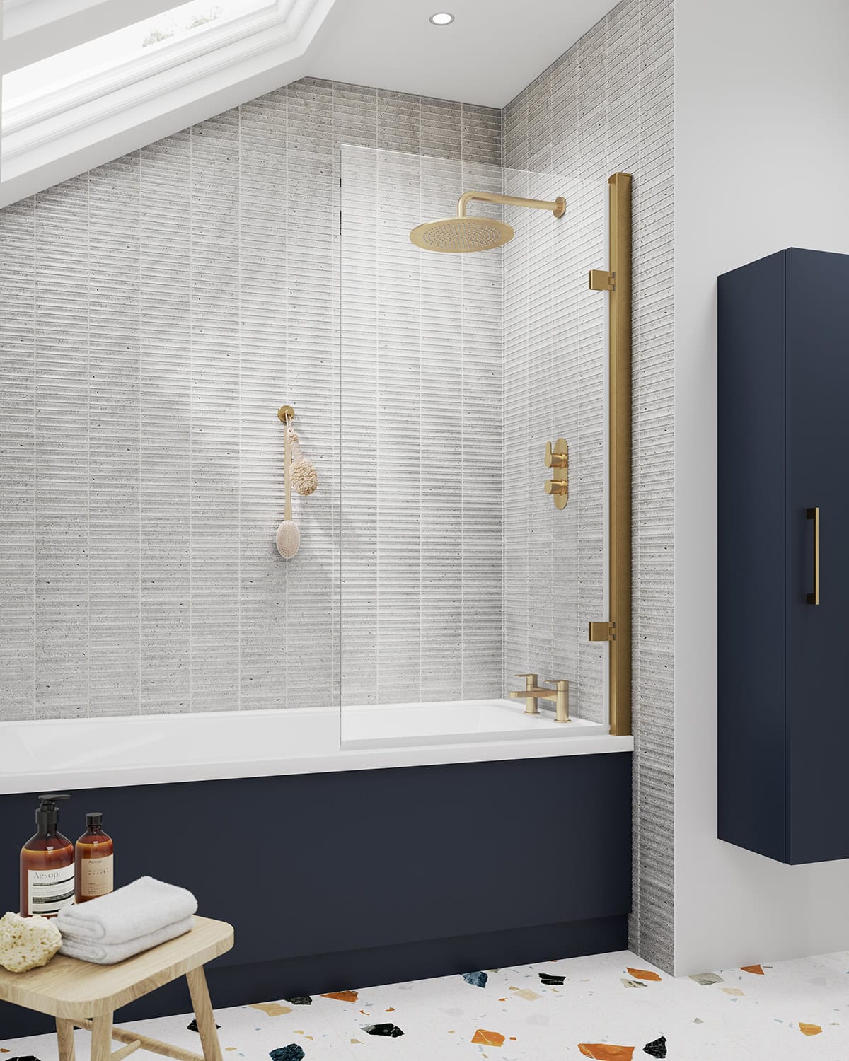 Bright, modern bathroom with a stylish bathtub, gold shower fixtures, and a blue wall-mounted cabinet, featuring a terrazzo floor and textured grey wall tiles, perfect for contemporary bathroom design.