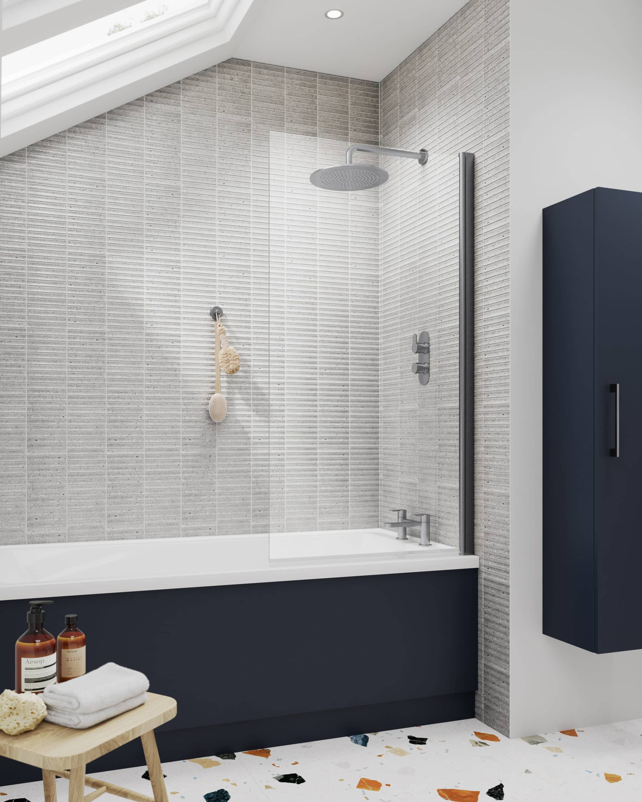 Contemporary bathroom shower area with minimalist design, grey textured tiles, ceiling-mounted rainfall shower, navy blue bath panel, and matching storage cabinet, creating a sleek, modern look with ample natural light.