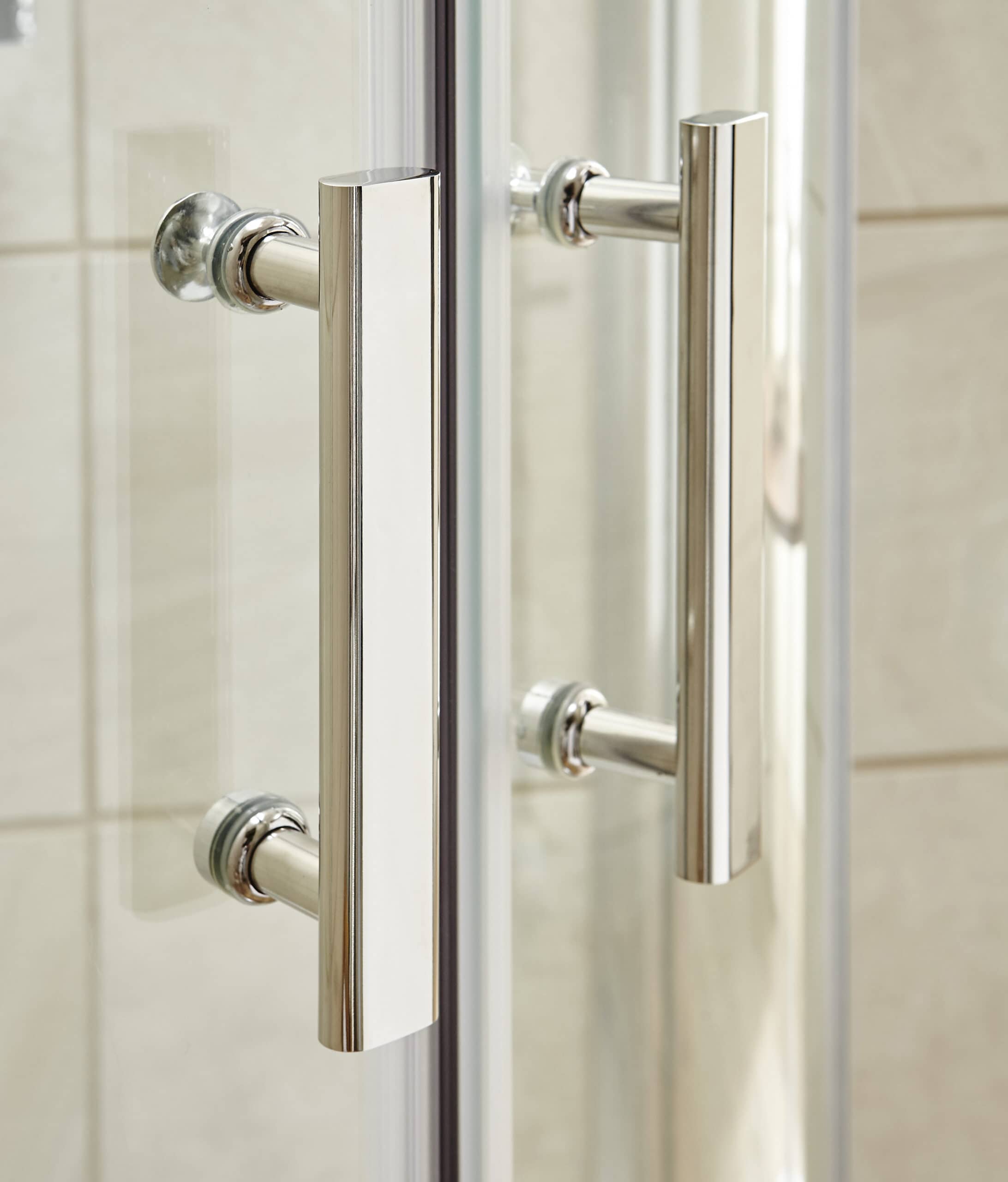 Sleek chrome bathroom door handles on glass shower enclosure, modern fixtures enhancing bathroom design.