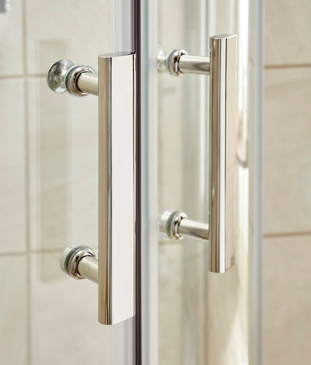 Sleek chrome bathroom door handles on glass shower enclosure, modern fixtures enhancing bathroom design.