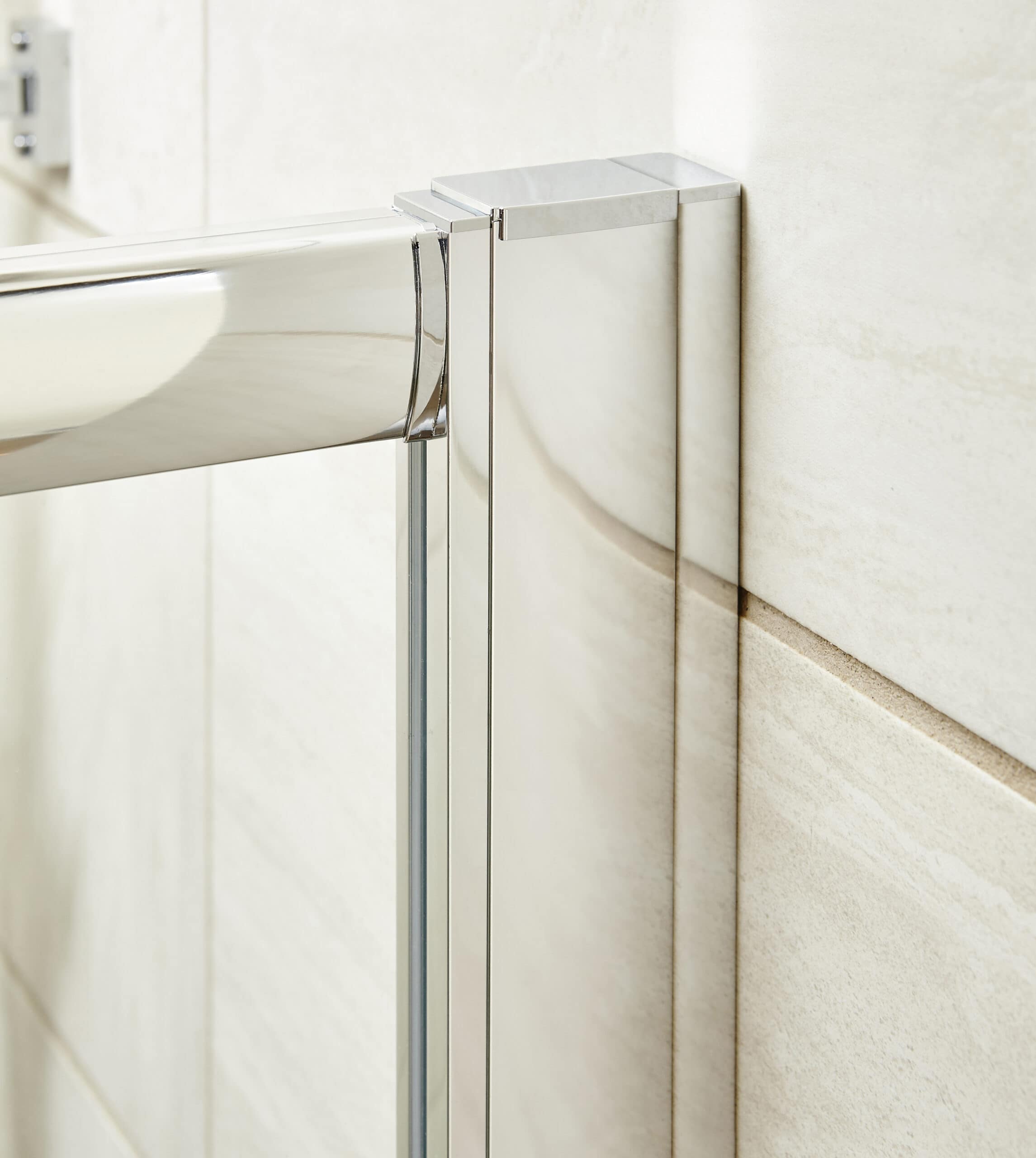 Sleek glass shower enclosure with chrome fittings in a modern bathroom, featuring beige wall tiles, emphasising contemporary design and bathroom renovation details.