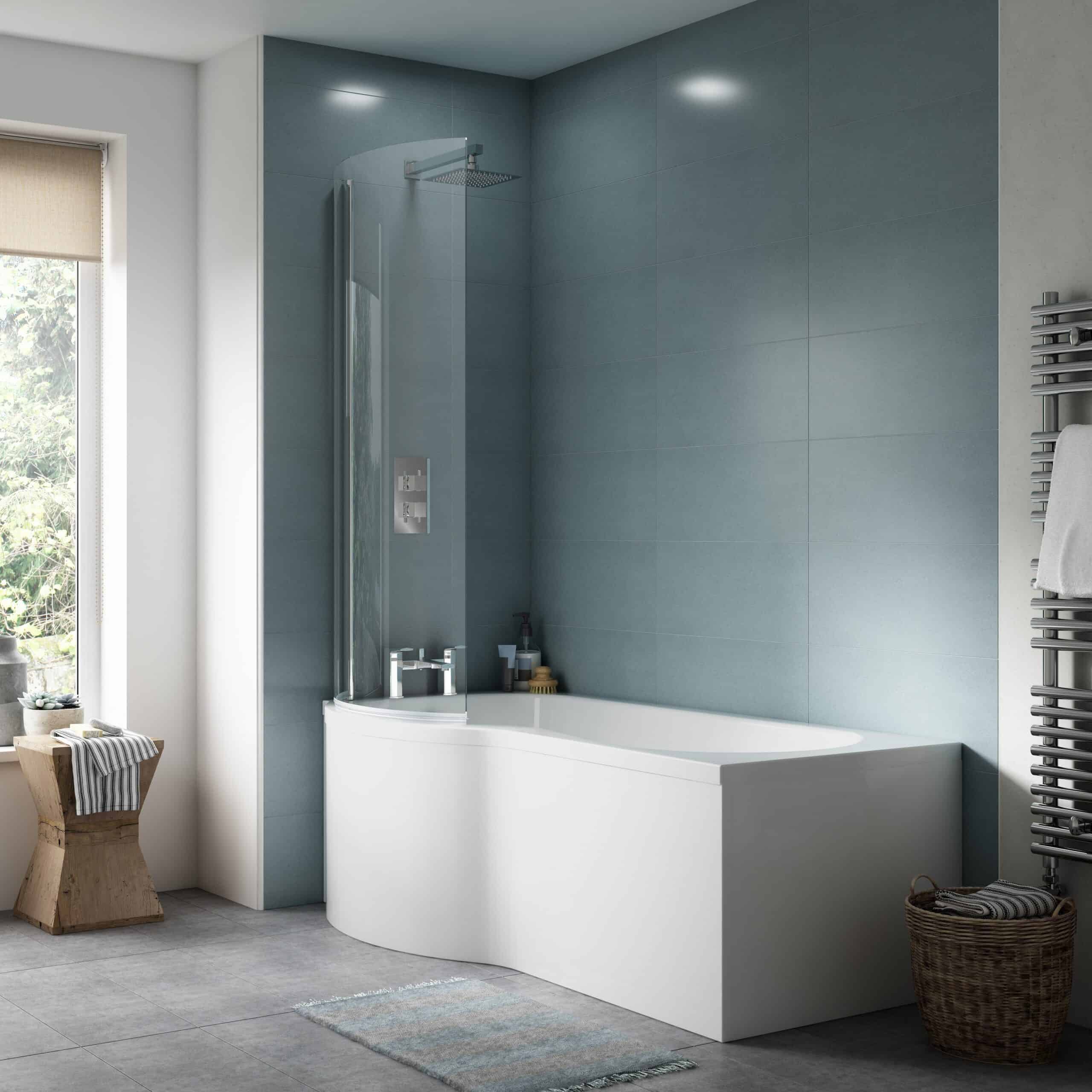 Contemporary white bathtub with a glass shower screen in a modern bathroom with blue tiled walls and grey flooring, featuring a heated towel rail and a wooden stool.