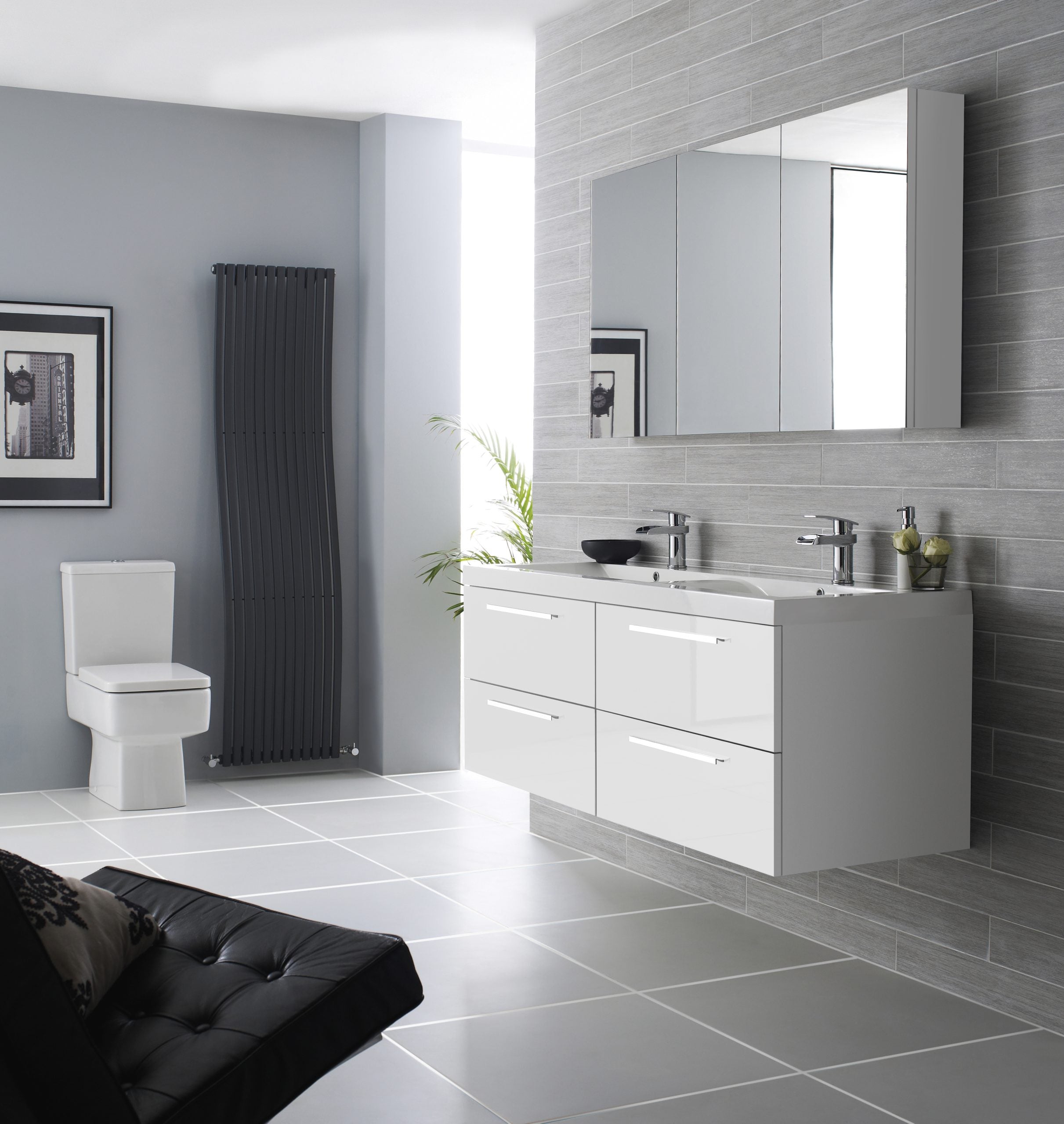 Modern white bathroom vanity with double sinks and mirrored cabinet, grey textured wall tiles, contemporary black radiator, and a sleek toilet in a minimalist bathroom design.