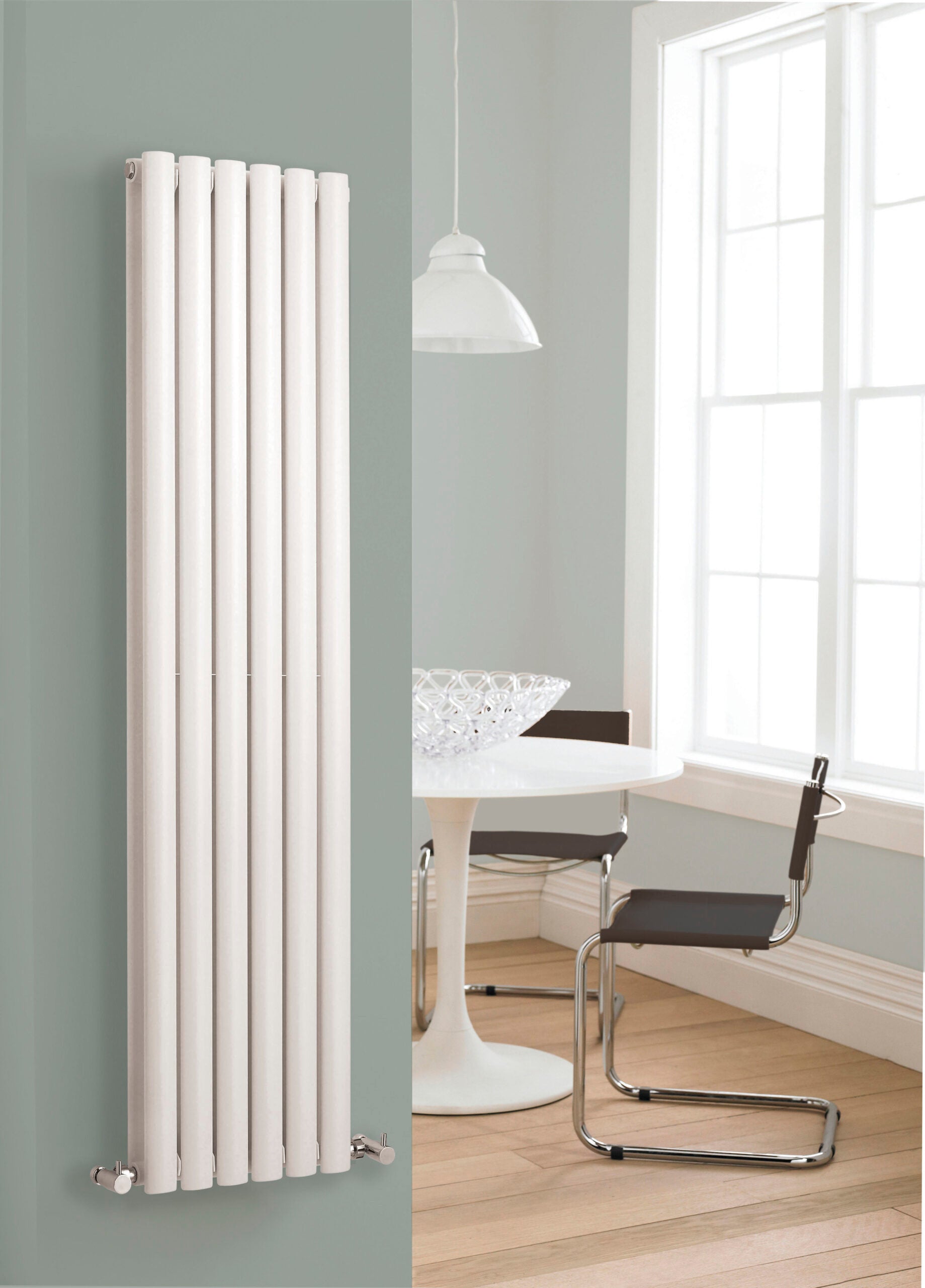 Modern white vertical radiator in a contemporary bathroom setting with a round white table and black chairs near a large window.