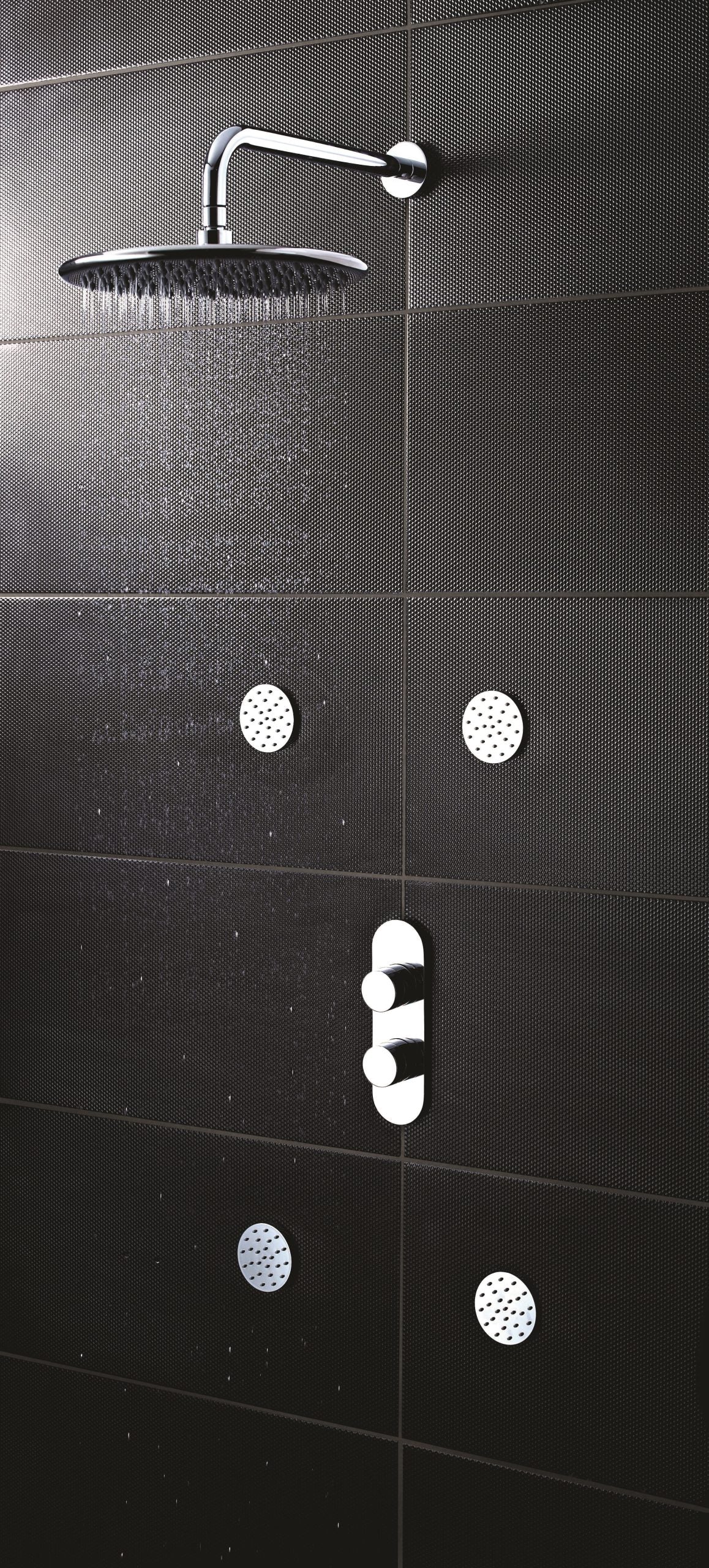 Shower head and controls with black textured bathroom tiles, modern shower fixtures.