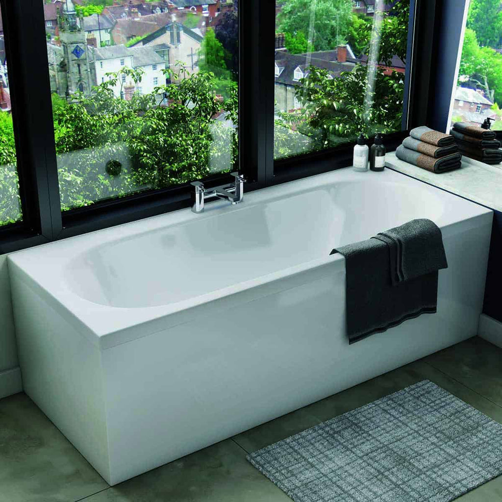 Clean modern freestanding white bathtub with black towels, soap bottles, and neatly folded towels on windowsill, overlooking lush greenery and a charming residential neighbourhood—perfect for a luxury bathroom upgrade.