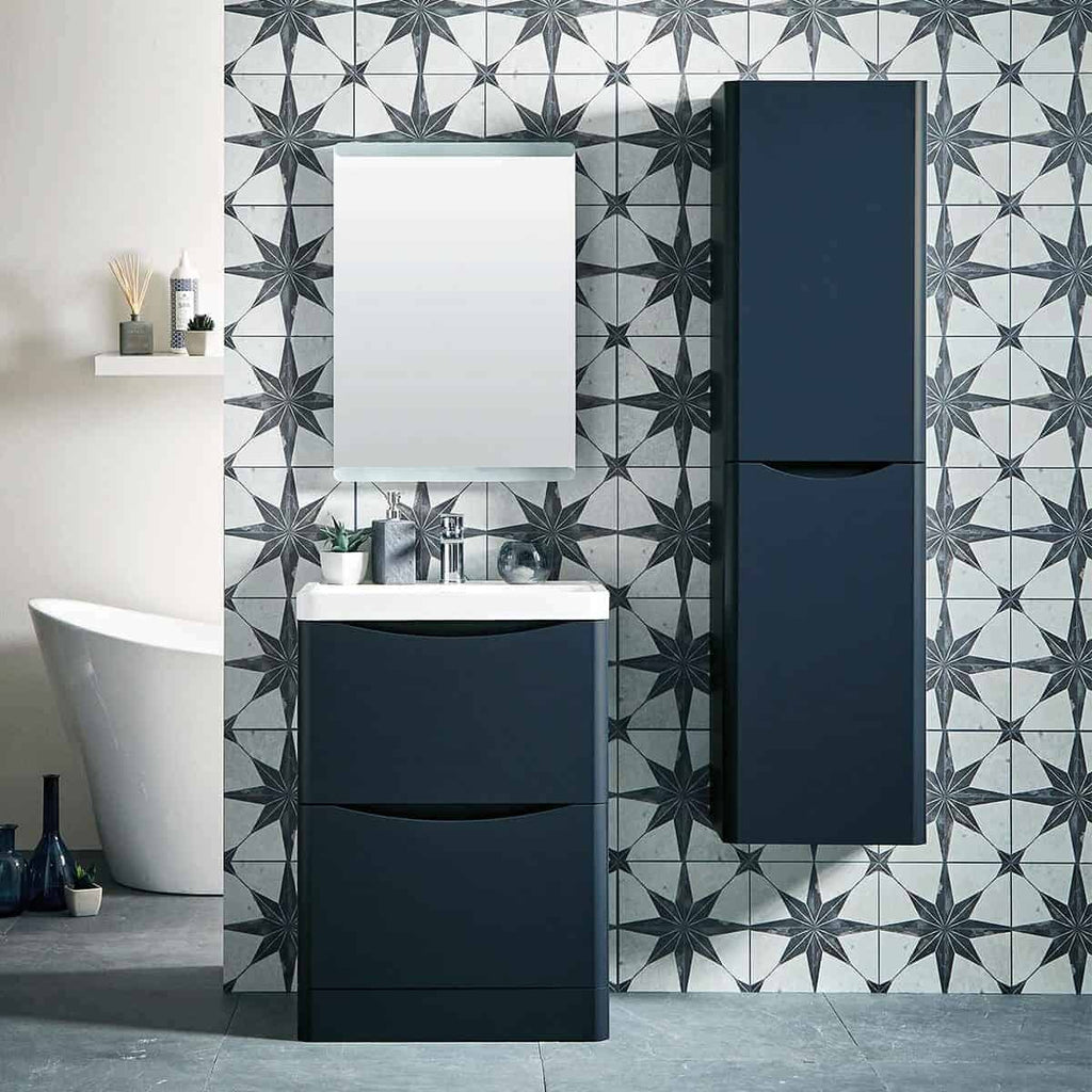 Modern navy blue bathroom vanity set with sleek sink, mirror, and tall cabinet against decorative geometric tile wall. Stylish bathroom storage solutions with contemporary design.