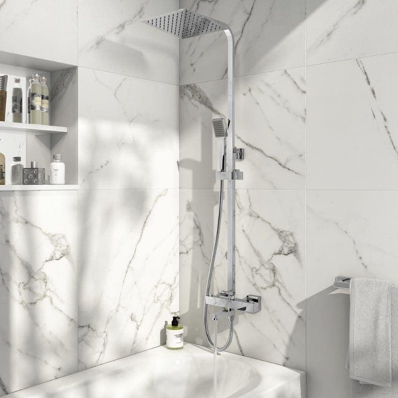 Showerhead and handheld shower in a modern white marble bathroom with built-in shelves.