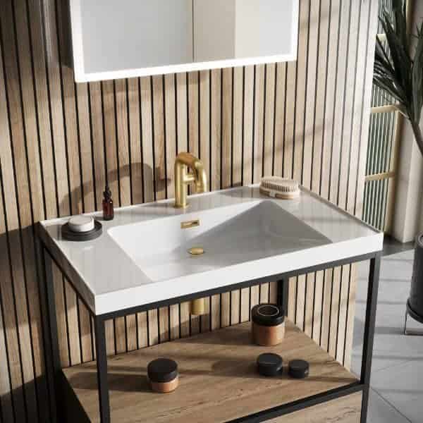 Brushed gold bathroom faucet with white countertop sink, wooden wall paneling, and modern decor, showcasing stylish and functional bathroom design.