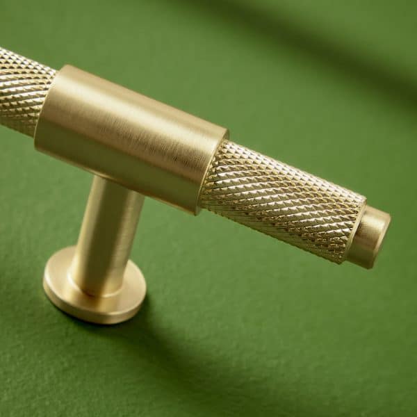 Shaving razor handle on a green surface with textured grip for comfortable use and precision.