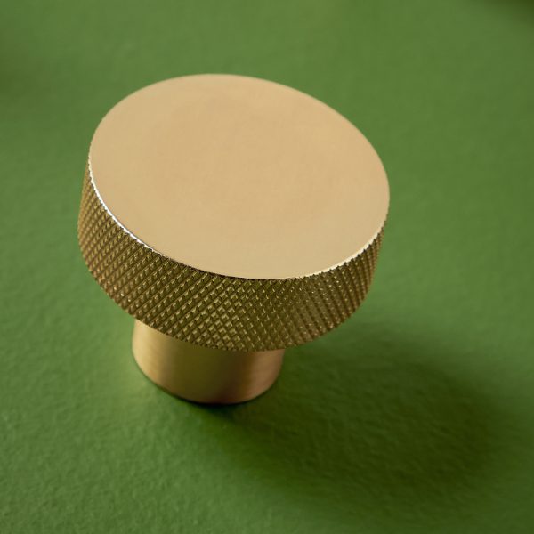 Gold bathroom knob on green background, luxurious bathroom fixture, modern gold knob for bathroom cabinetry.