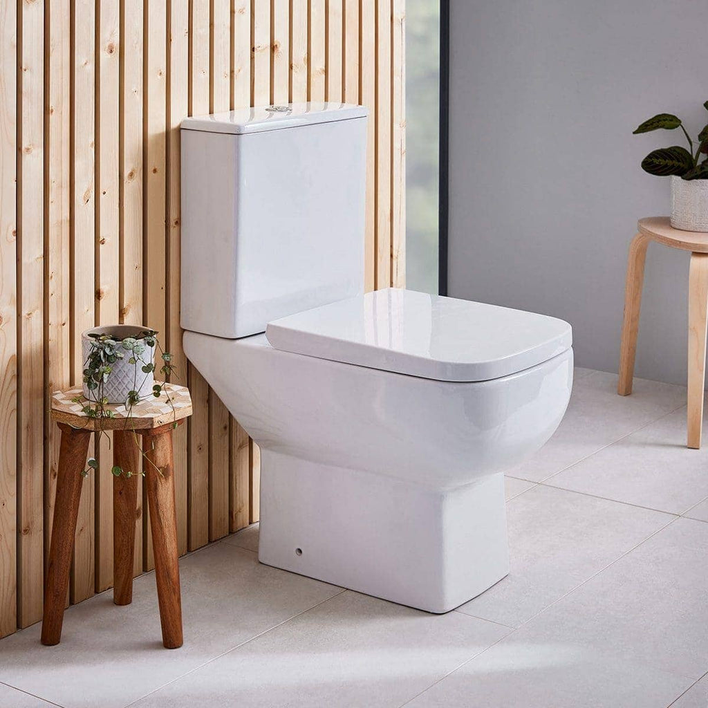 Sleek white modern toilet in a contemporary bathroom with wooden wall paneling, decorated with potted plants and natural light, showcasing stylish and functional bathroom fixtures.