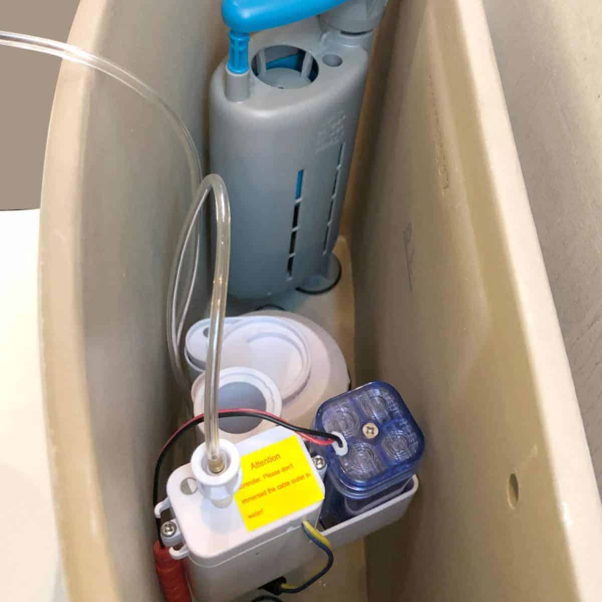 Relay device inside toilet cistern, part of the toilet flush system, with wiring and components visible for maintenance or repair.