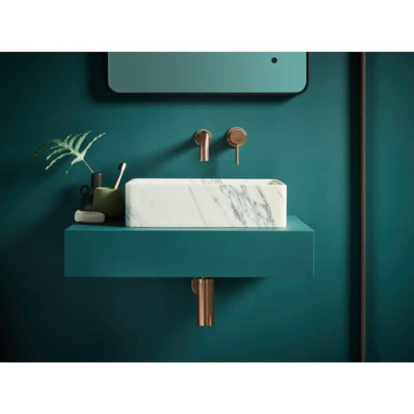 Minimalist bathroom vanity with a white marble sink and modern brass fixtures on a rich teal wall. Stylish and contemporary design perfect for any luxury bathroom renovation.