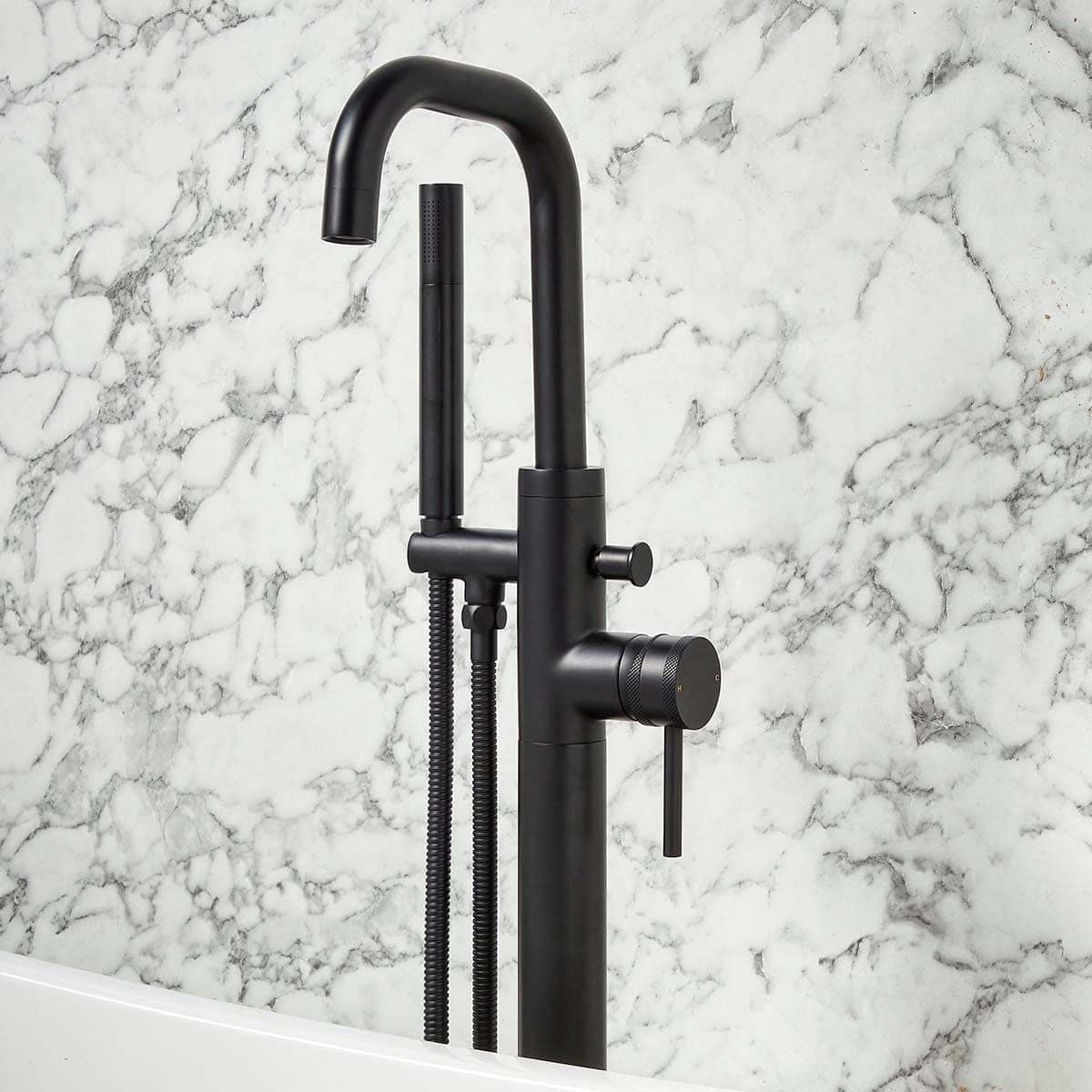 Brushed black kitchen sink tap with flexible hose and modern design in front of marble wall, stylish bathroom or kitchen fixture for contemporary homes.