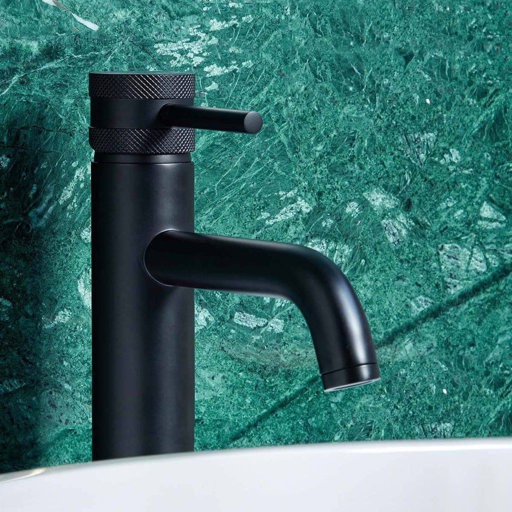 Sleek black bathroom tap with matte finish against a green marble wall, modern bathroom fixtures, stylish and contemporary design.