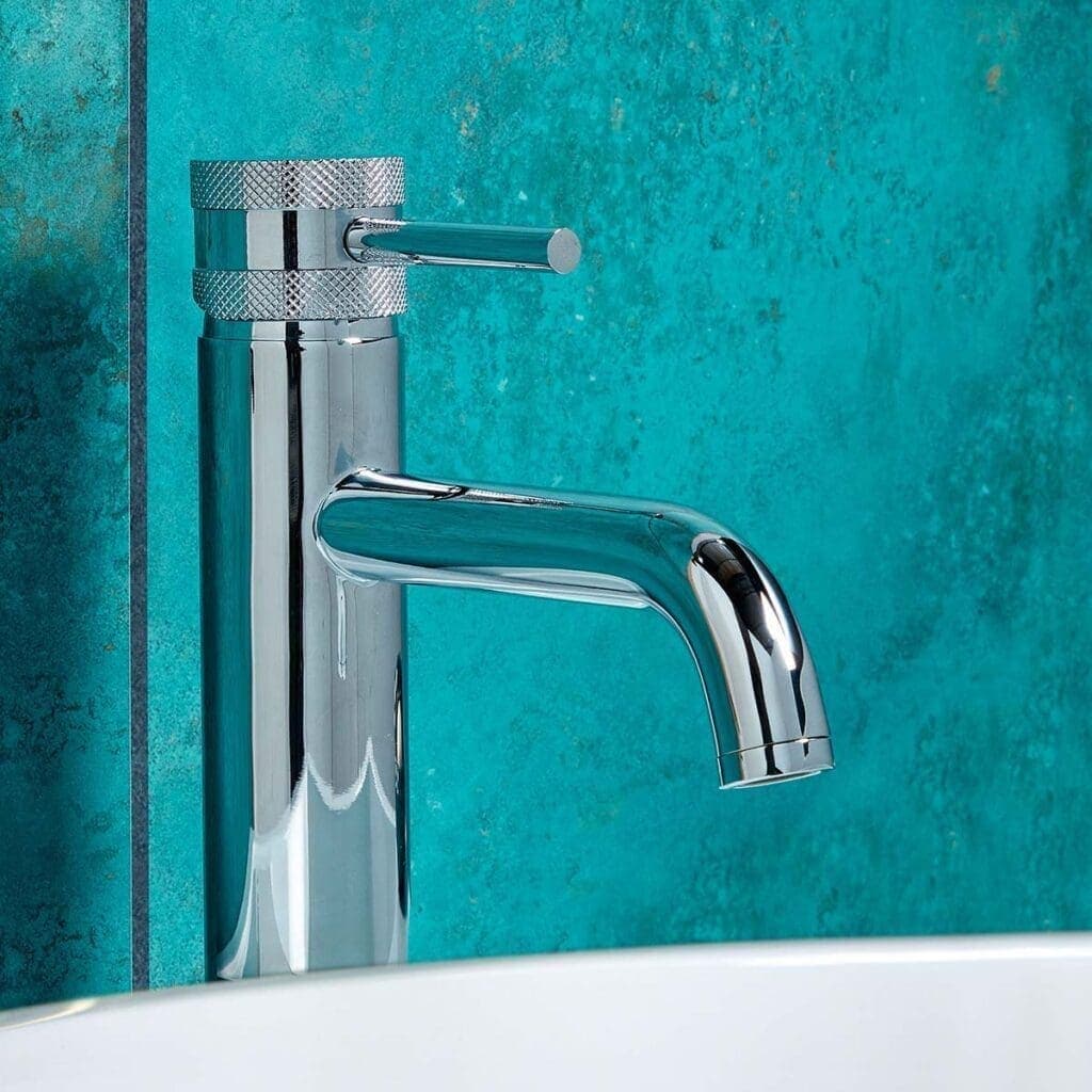 Polished chrome bathroom tap on vibrant teal wall, modern and stylish design.