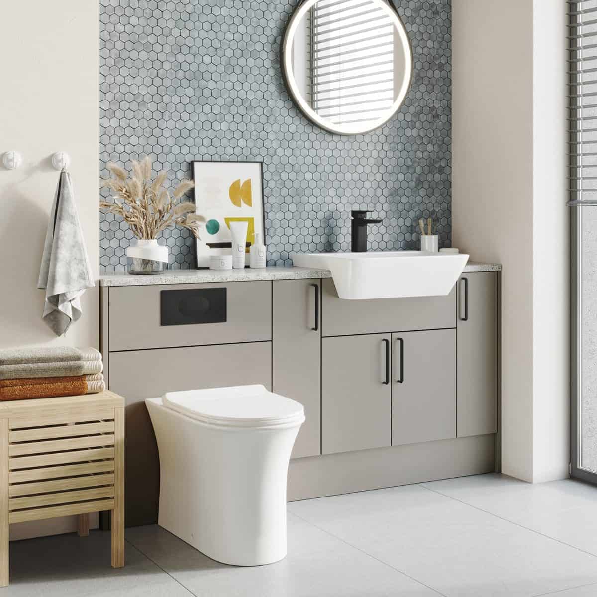 Sleek modern bathroom with wall-mounted sink, grey cabinetry, round mirror, and earthy tones, showcasing contemporary bathroom design and fixtures.