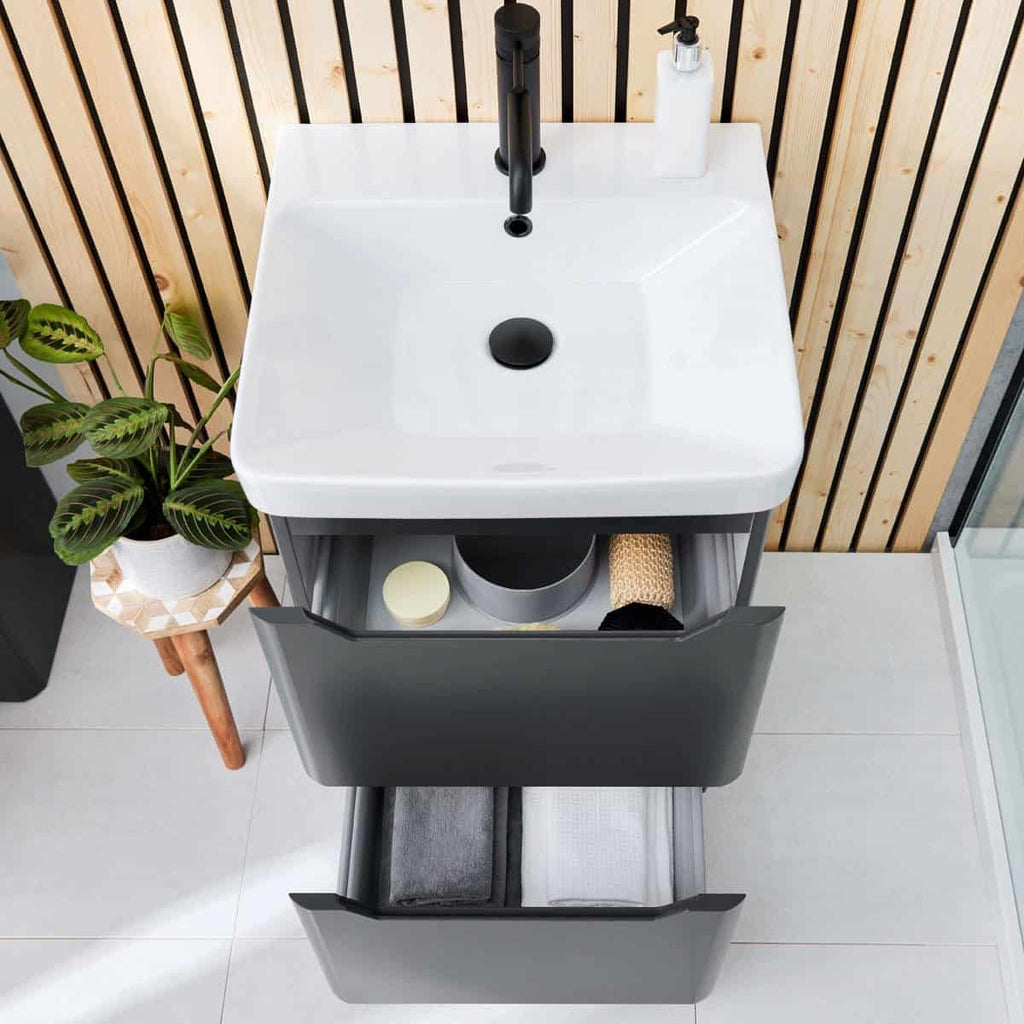 Contemporary bathroom vanity with integrated sink, black tap, and storage drawers, featuring a wood panel wall and potted plant for modern, stylish bathroom décor.