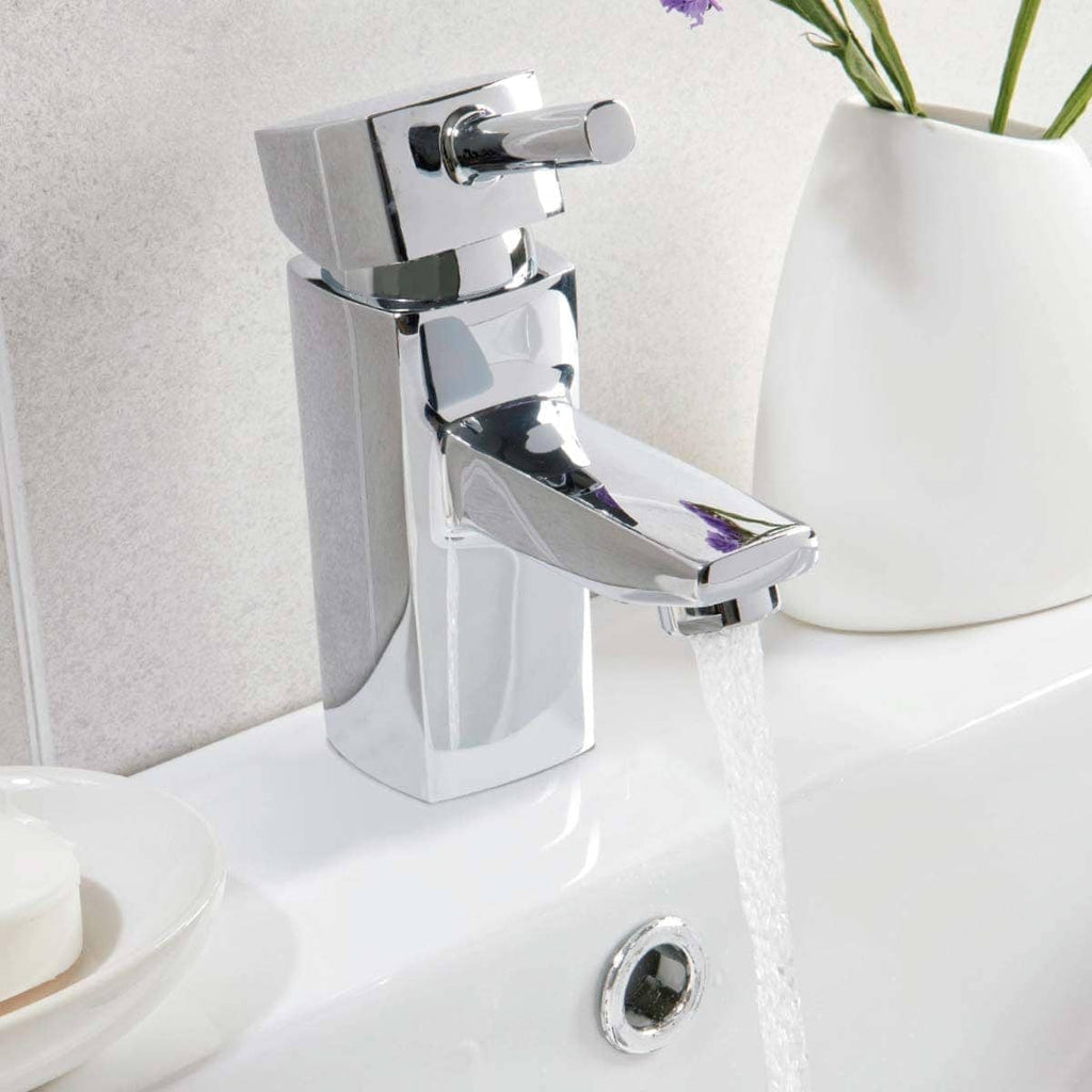 Shiny chrome bathroom tap with flowing water in a modern bathroom setting.