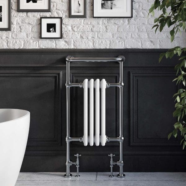 Vintage style white vertical radiator with chrome pipe frame in modern bathroom setting.