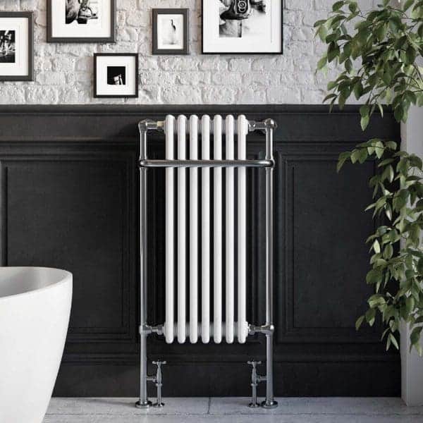 Traditional white vertical radiator in a modern bathroom with black paneling, framed art, and greenery for a stylish and functional bathroom decor.