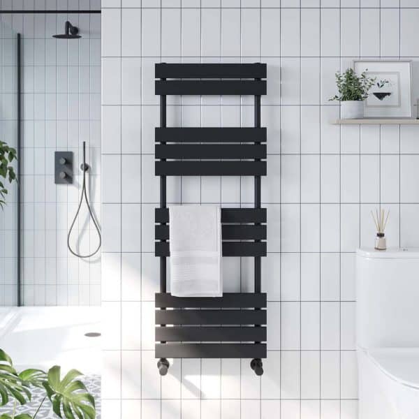 Industrial black heated towel rail in a modern bathroom with white tiled walls, featuring a white towel and stylish decor, perfect for contemporary bathroom heating and towel drying solutions.