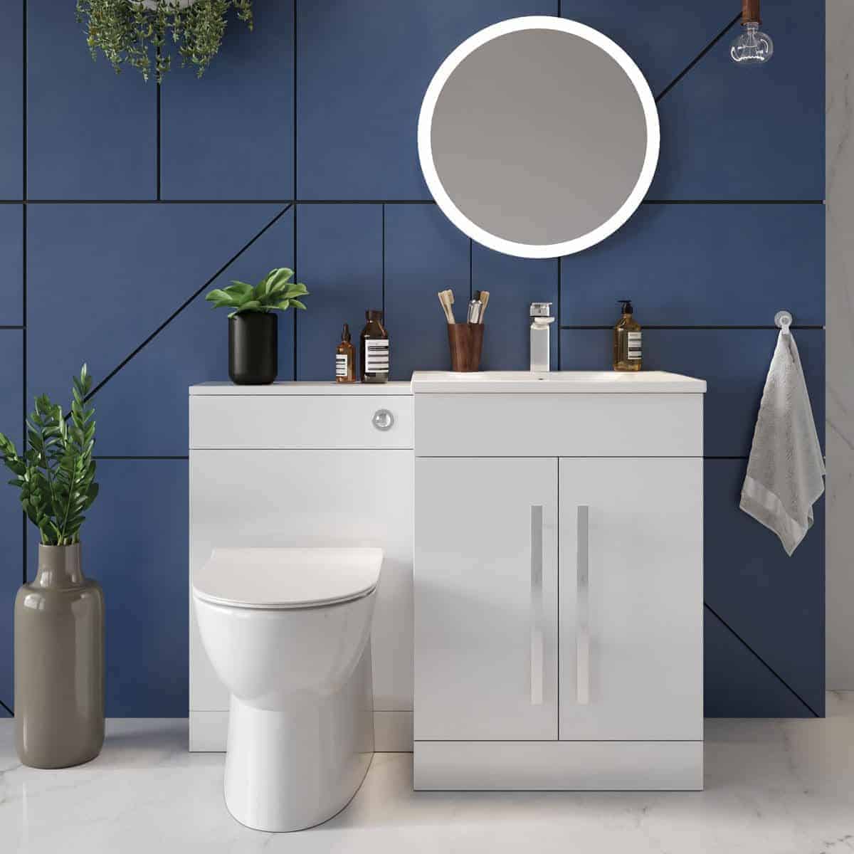 Sleek white bathroom vanity and toilet set against a modern navy blue tiled wall with plants and bathroom accessories, styled for contemporary bathroom design.