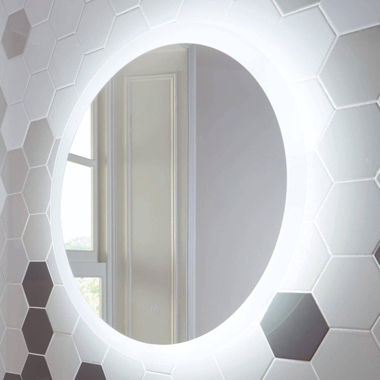 Mirror with integrated LED lighting in a modern bathroom, surrounded by white hexagonal ceramic tiles, showcasing contemporary bathroom decor and design.
