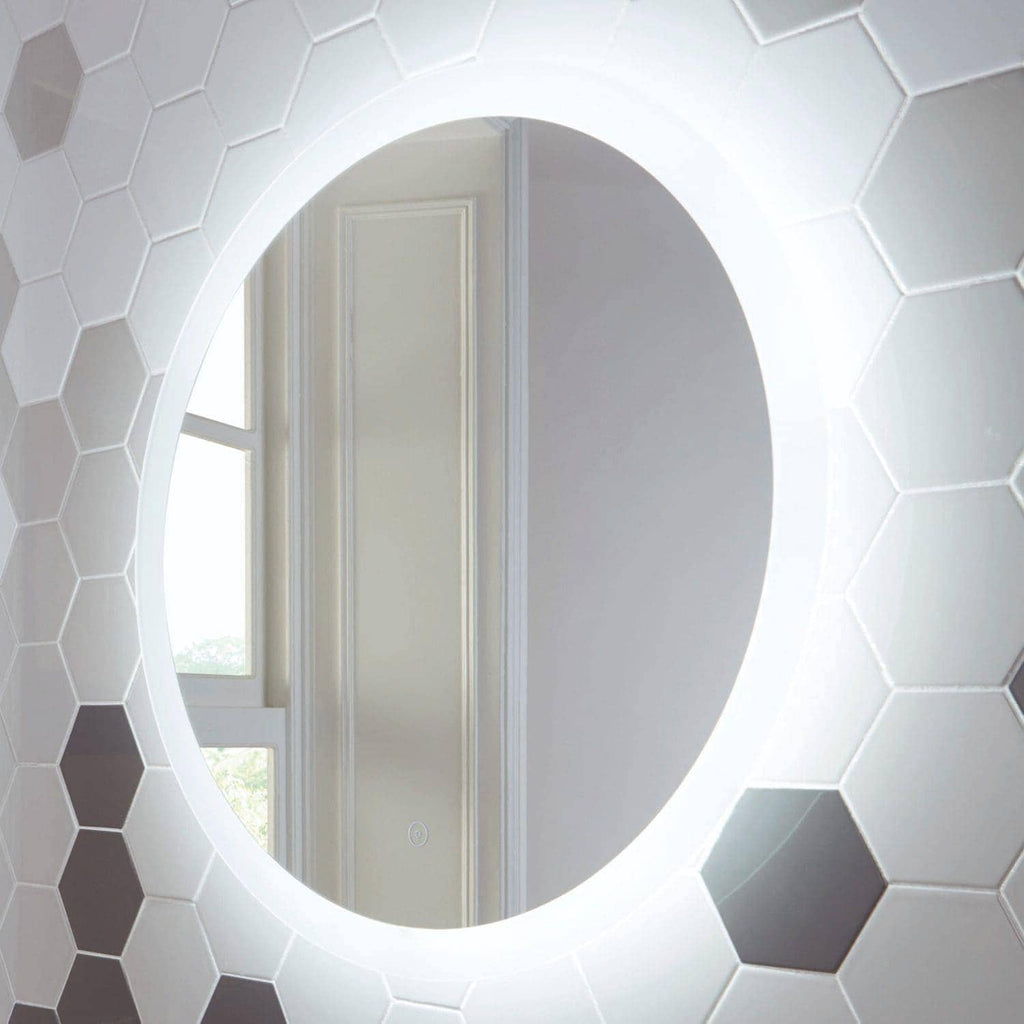 Polished round mirror with LED backlighting in a modern bathroom, surrounded by white hexagonal tiles, creating a sleek and contemporary bathroom design.