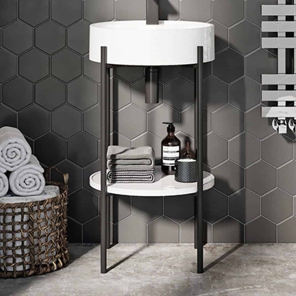 Stylish bathroom storage stand with a white circular lamp, towels, soap dispenser, and decorative accessories against grey hexagonal wall tiles. Ideal for modern bathroom decoration.
