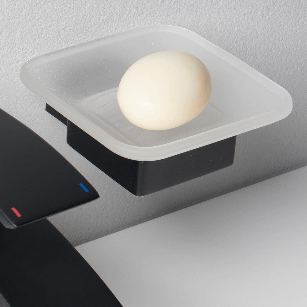 Soft white bath bomb resting on a soap dish in a modern bathroom setting, designed to enhance relaxation and elegance, perfect for luxurious bathroom decor and self-care routines.