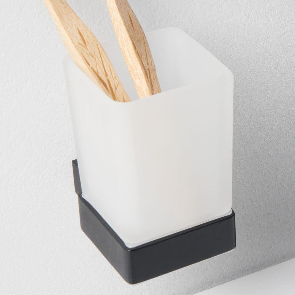 Minimalist bathroom accessory with wooden tongs in a sleek white and black wall-mounted holder, designed for functional and modern bathroom storage solutions.