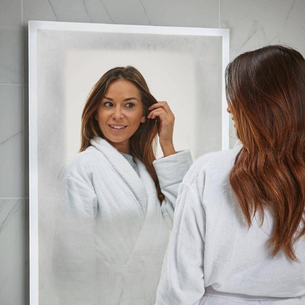 Shower-proof mirror reflection of a woman in a white bathrobe, perfect for modern bathroom design and mirror installations at Bubly Bathrooms.