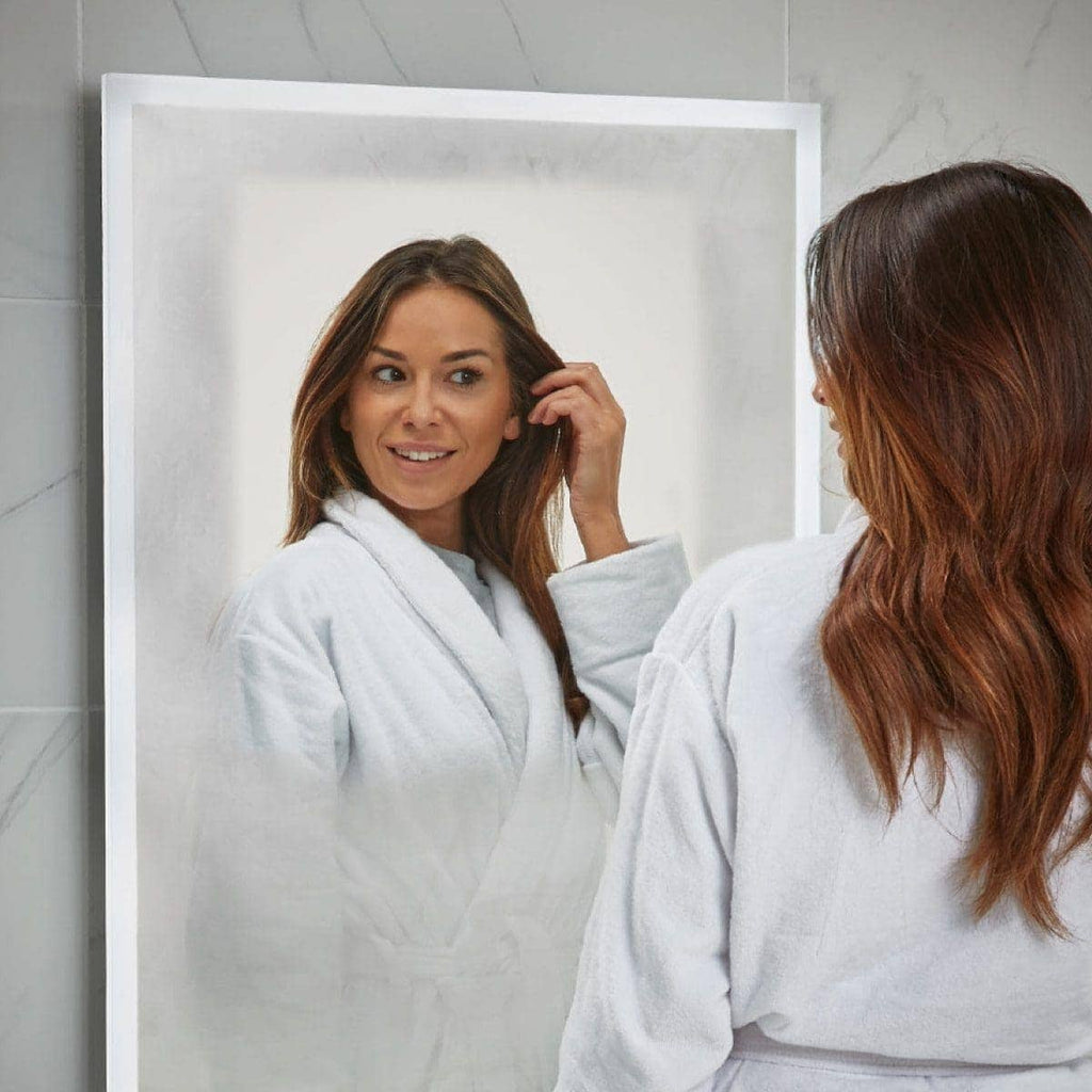 Shower-proof mirror reflection of a woman in a white bathrobe, perfect for modern bathroom design and mirror installations at Bubly Bathrooms.