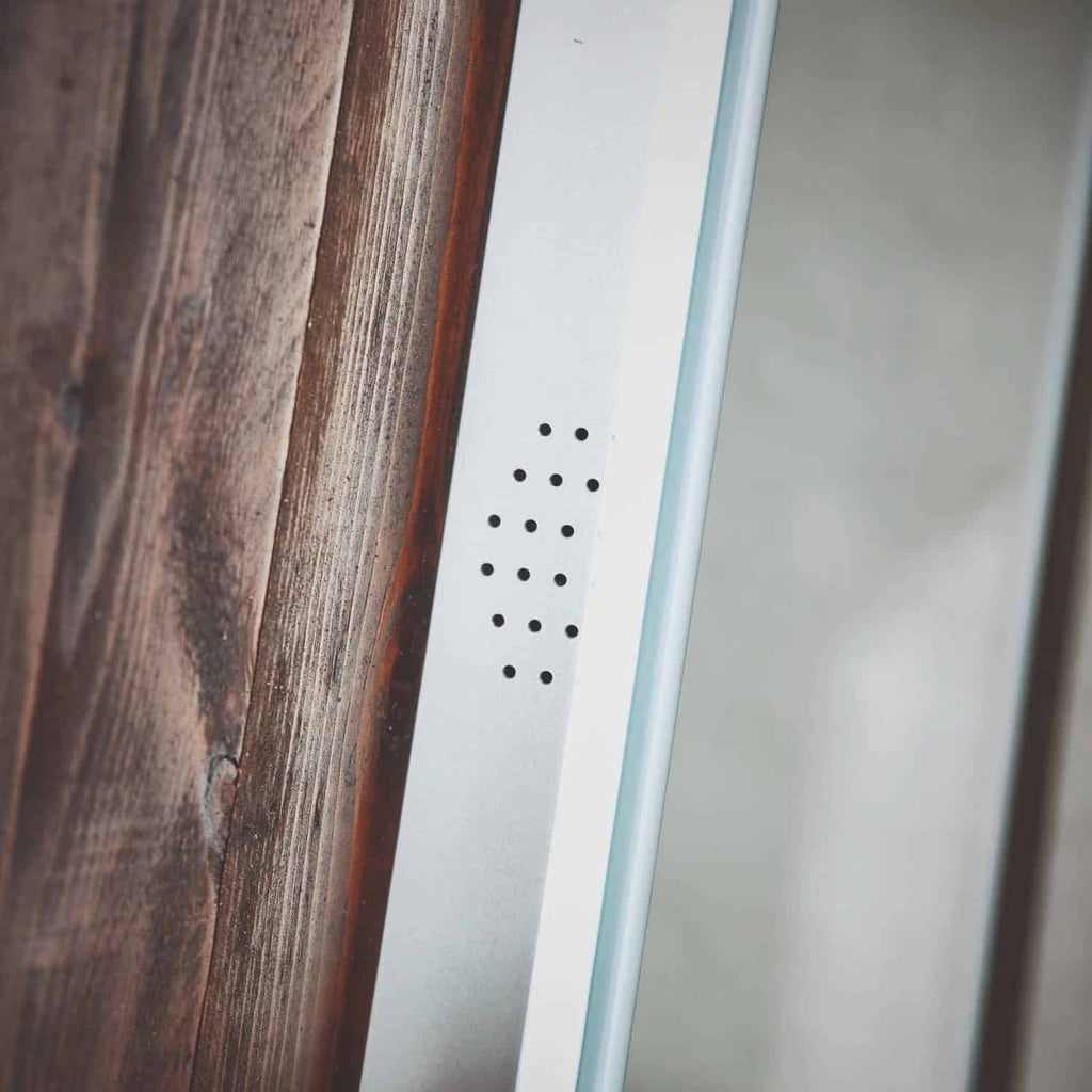 Aluminium shower panel with black drainage holes next to a wooden wall for modern bathroom design.