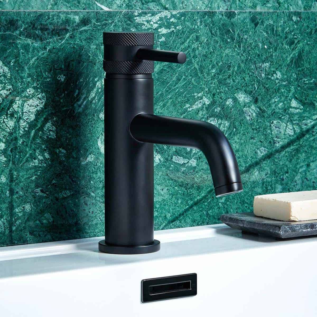Sleek black bathroom tap with modern matte finish set against green marble wall, blending style and functionality in contemporary bathroom design.