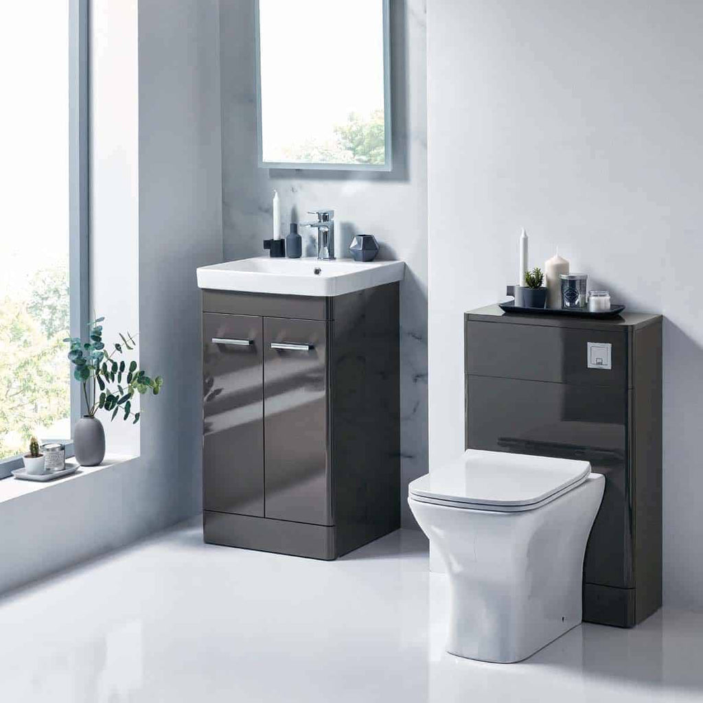 Sleek modern bathroom with a grey vanity unit, contemporary toilet, and minimalistic decor featuring candles and small plants, ideal for stylish bathroom design inspiration.