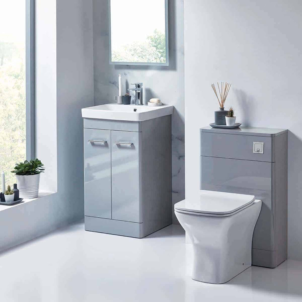 Modern grey bathroom vanity with integrated sink and stylish storage cabinets, complemented by a sleek toilet and minimalist decor, creating a contemporary and functional bathroom space.
