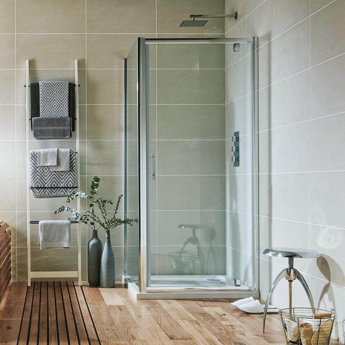 Modern glass shower enclosure in contemporary bathroom with beige tiled walls and wooden floor, complemented by sleek accessories and towel racks.