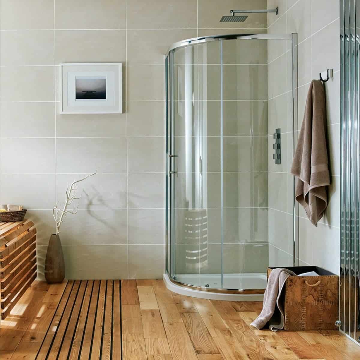 Modern beige tiled bathroom with curved glass shower cabin, wooden flooring, and minimalist decor, showcasing luxury and style in contemporary bathroom design.