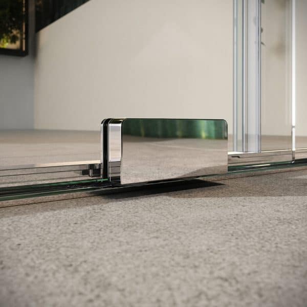 Sliding shower door metal bottom track with reflective finish on a grey carpeted bathroom floor.