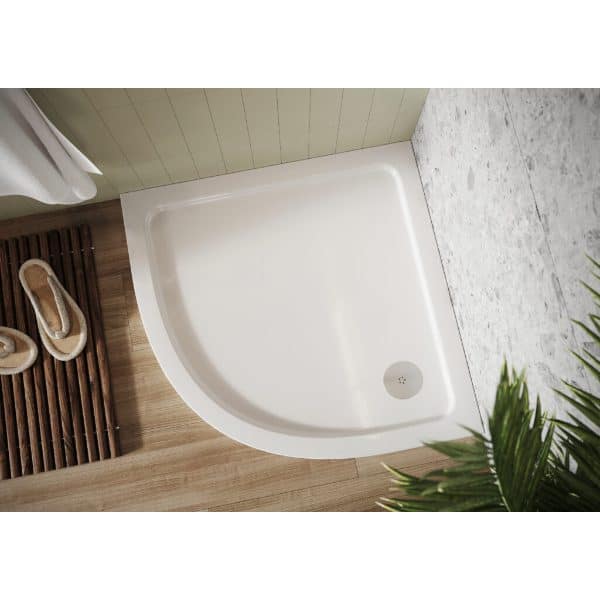 Modern white shower tray with curved edge, set against light green wall panel and wooden flooring, featuring a drain in corner, ideal for contemporary bathroom renovation.
