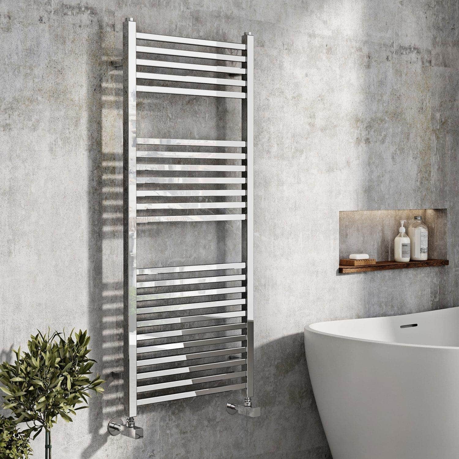 Modern chrome towel radiator in a contemporary bathroom with a freestanding bathtub, minimalist shelving, and grey textured walls, perfect for stylish bathroom heating solutions.