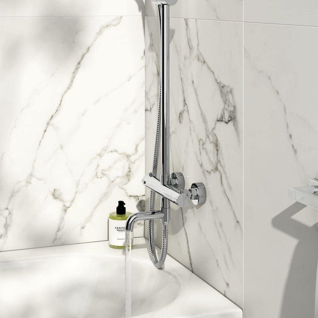 Polished chrome shower mixer and adjustable handheld shower head mounted on white marble tiled wall in modern bathroom.
