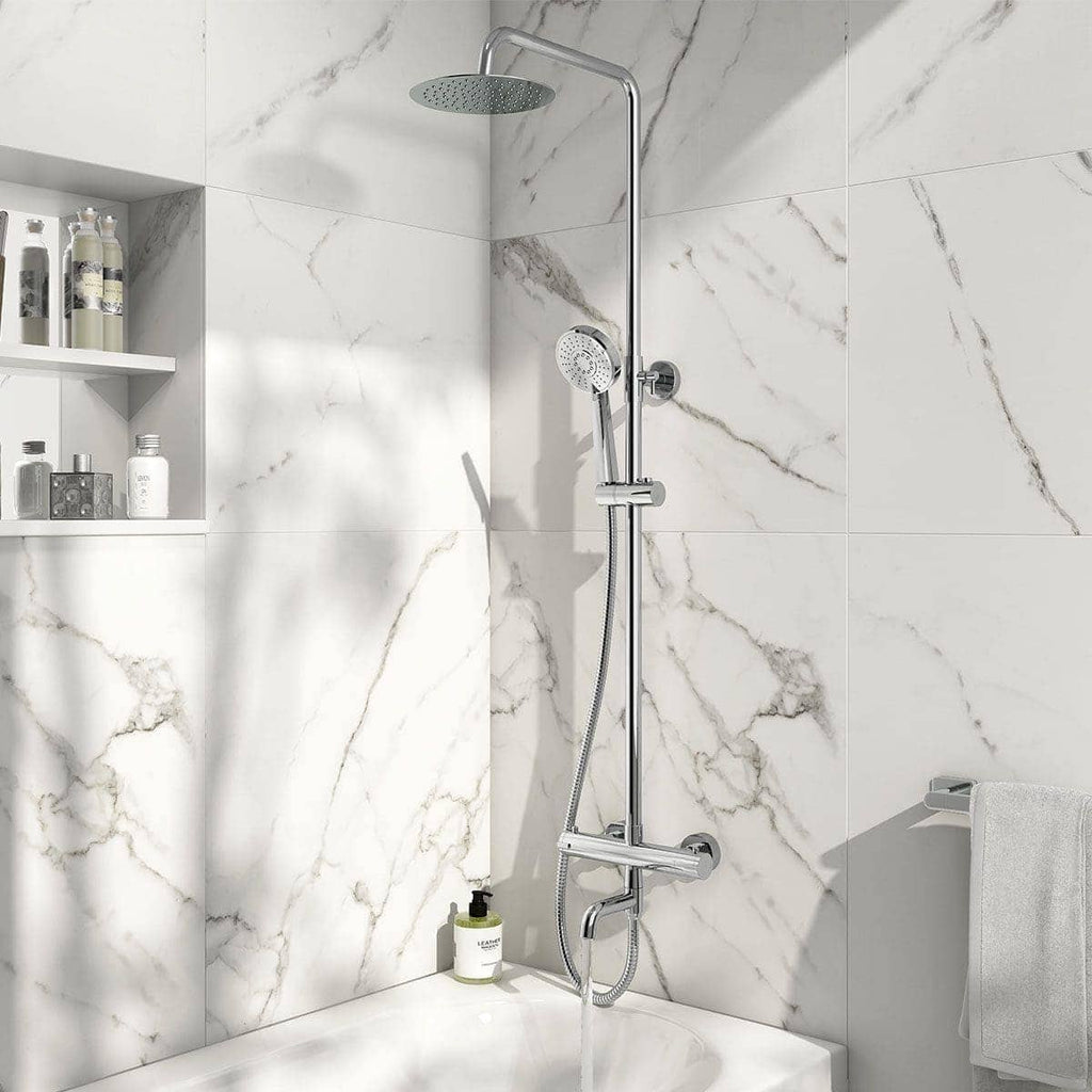 Polished chrome shower rail with overhead rain shower and handheld shower head in a modern marble-tiled bathroom.