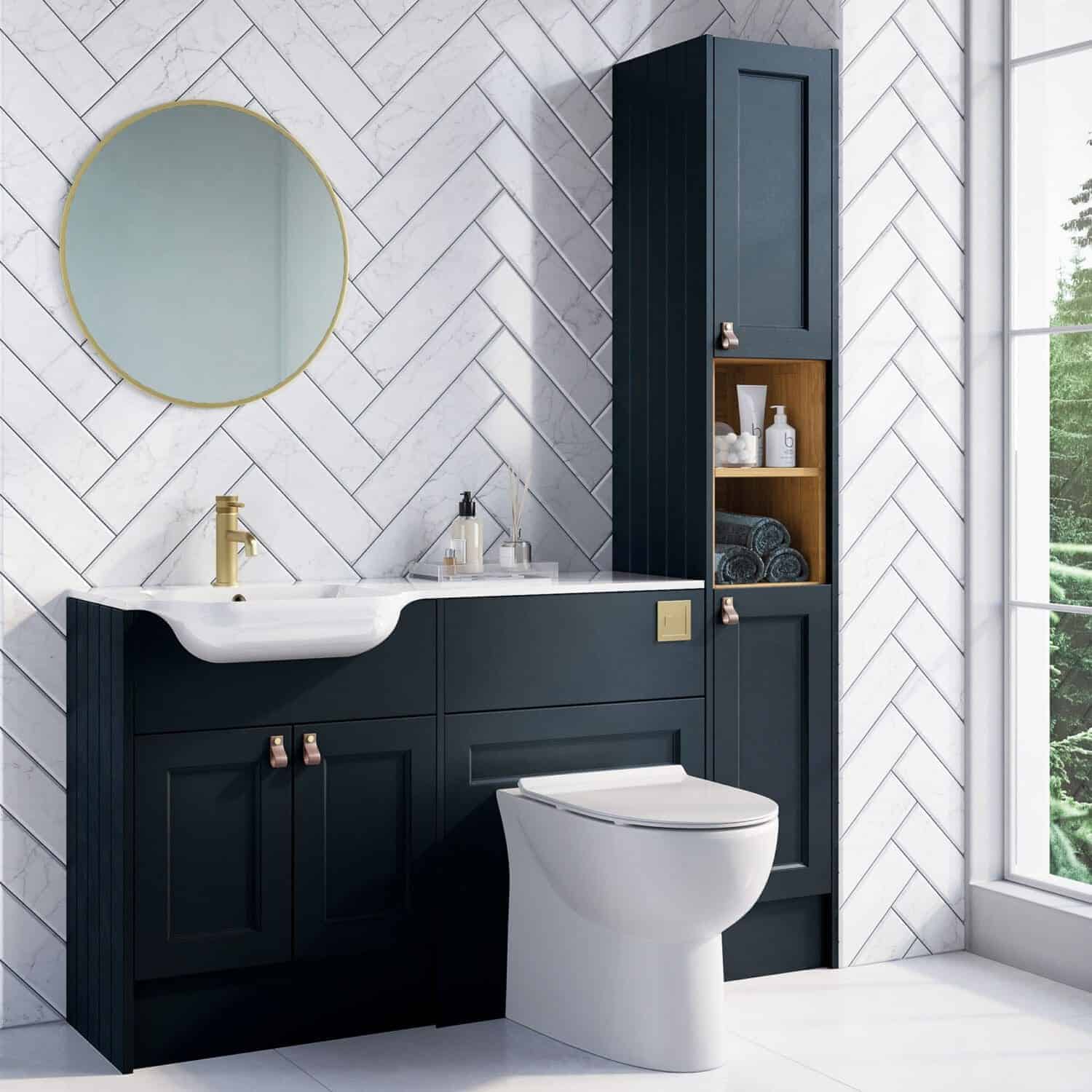 Contemporary navy bathroom vanity with white sink and gold fixtures, tall storage cabinet, oak shelving, white marble wall tiles, and large window with views of greenery.